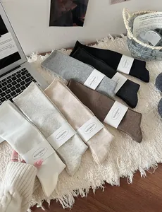 Set of seven ribbed knit knee-high socks in assorted neutral tones on a plush rug