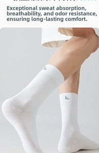 Close-up of white cotton crew socks featuring a small blue label and ribbed cuffs on model