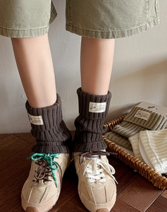 Close-up of ribbed knit leg warmers with cartoon textile label in three colors