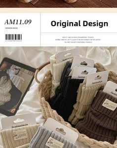 Detail of multi-color ribbed knit leg warmers with woven labels in a cozy home setting