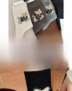 Detailed close-up of wool crew socks featuring cute 3D plush dog designs in earth tones