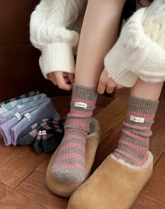Close-up of thick pink and grey striped wool socks with a white quote woven label