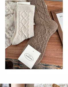 Detailed macro view of cream and brown cable knit wool socks with diamond texture