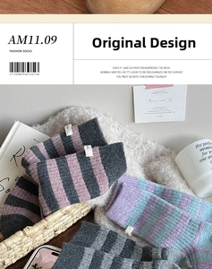 Close-up of thick striped wool socks with brand label in a cozy home setting