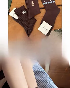Detailed view of three brown knit mid-calf socks with embroidery and ribbed patterns