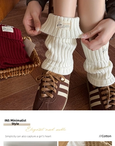Macro shot of knitted cotton leg warmers with cable knit texture and branded label
