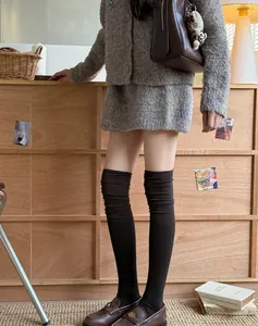 Close-up of black knitted over-the-knee socks with vertical texture and academic style