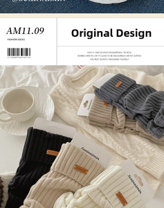 Detail of grey cable knit leg warmers with brown leather label and soft wool texture