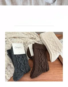 Close-up of cable knit wool socks in dark grey, brown, and cream with elastic cuffs