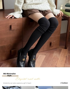 Detail of black knitted over-knee cotton socks with vertical ribbed texture and wide cuffs