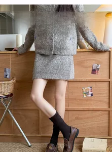 Close-up of knit texture on oatmeal long-sleeve cardigan and matching mini skirt