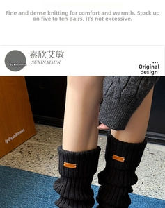 Close-up of black cable-knit leg warmers featuring a vintage orange leather brand tag