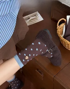 Detailed close-up of brown polka dot crew socks with blue trim and cute bear embroidery