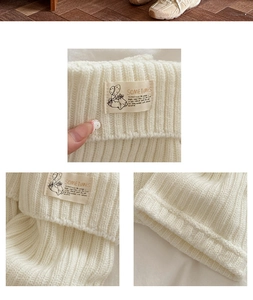 Detail of cream white cable knit leg warmer featuring a decorative SOMETIMES fabric label