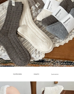 Close-up of thick ribbed wool socks in earth tones showing textured knit detail and paper labels