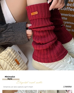 Detail of burgundy and beige knitted leg warmers with vintage leather labels