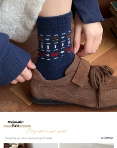 Detail of navy cotton crew socks with bear and heart jacquard patterns and brown sneakers