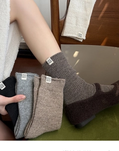 Detailed close-up of thick ribbed wool socks with woven label in earthy neutral tones