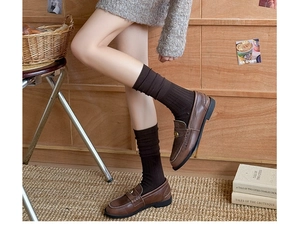 Detail of ribbed dark brown crew socks styled with vintage leather loafers and buckles