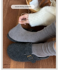 Details von grauen gerippten Socken mit Filz-Mules und Schnallen auf Holzboden