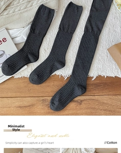 Detail of grey cotton ribbed over-knee socks displayed on a textured cozy carpet