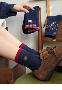 Detail of navy blue knit socks featuring red cuffs and cute bear embroidery pattern