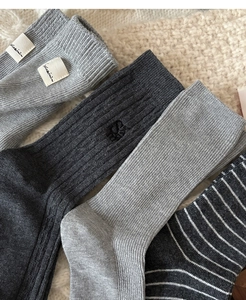 Gros plan de chaussettes en coton côtelé gris avec logo brodé sur fond en maille douce