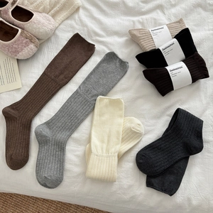 Flat lay of ballet style ribbed knit socks in neutral tones like grey and caramel