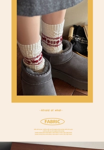 Close-up of Fair Isle wool socks with red elk pattern styled with grey winter snow boots
