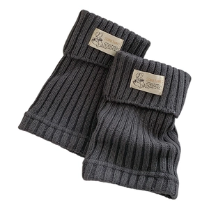 Dark gray knitted leg warmers with vintage ribbed texture and woven label for winter wear