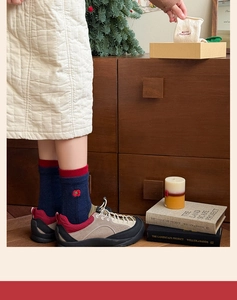 Detail of navy blue Christmas sock with floral embroidery and red ribbed cuff design