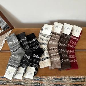 Winter wool socks for women with Nordic snowflake patterns in seven vintage colors on wood