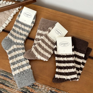 Trois paires de chaussettes en laine à rayures en tricot torsadé sur fond en bois
