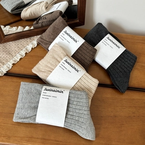 Minimalist ribbed knit crew socks in neutral grey, beige, and coffee tones on wood