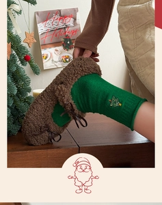 Detailed view of festive green knit socks with Christmas tree embroidery and plush slippers