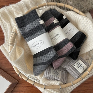 Warm grey striped wool socks and ribbed knit hat set in a cozy woven basket display