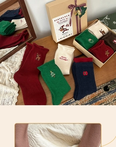 Detail of Christmas socks with embroidery in a kraft gift box with red ribbon and bell