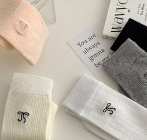 Detailed overhead view of assorted mesh bow socks in pink, cream, white, grey, and black