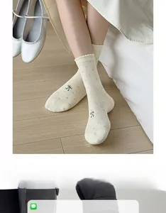 Detail of white knit crew socks with black bows and scalloped lace cuffs in a sweet style