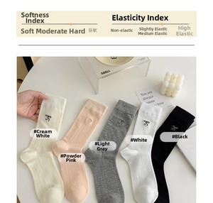 Detail of five colors of knit mid-calf socks with delicate bow embroidery and vertical texture