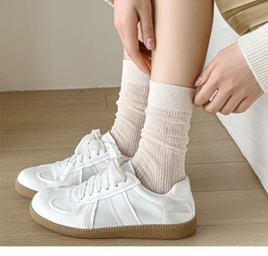 Detail of soft pink ribbed socks with bow accent paired with white retro sneakers