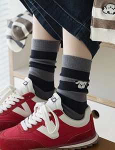 Detail of striped cotton socks featuring cute cartoon dog embroidery and red sneakers
