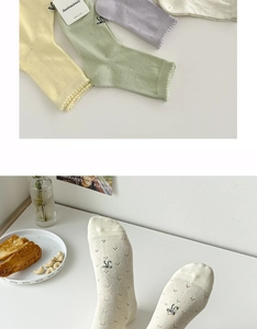 Detail of white cotton crew socks with bow embroidery, hollow out lace and wavy cuffs