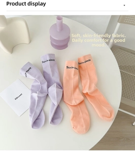 Close-up of pastel purple and orange ribbed cotton mid-calf socks with letter embroidery