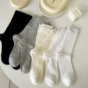 Set of four ribbed mid-calf socks in black, grey, beige, and white with cotton blend texture