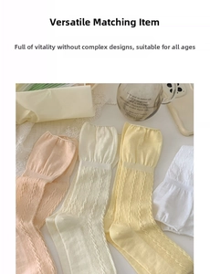 Detail of cable knit crew socks featuring ruffle edges in pastel pink and beige colors