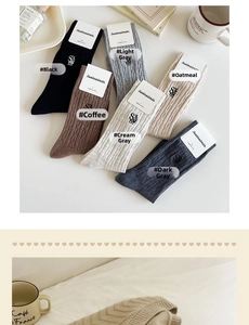 Flat lay of six-color ribbed cotton crew socks in earth tones with brand tags on a desk