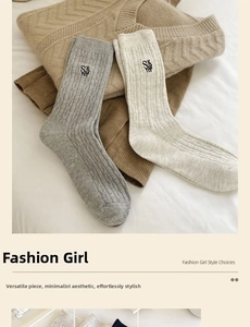 Close-up of knit crew socks with vertical stripes and letter embroidery on soft fabric