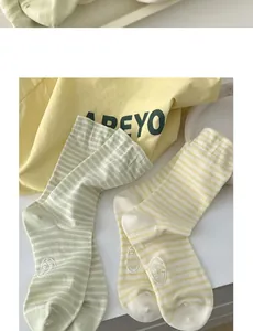 Detail of striped cotton crew socks in pastel yellow and green with custom embroidery