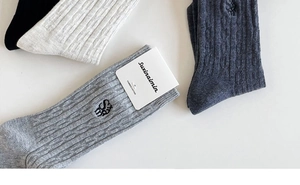Detailed macro view of combed cotton texture and letter embroidery on ribbed crew socks